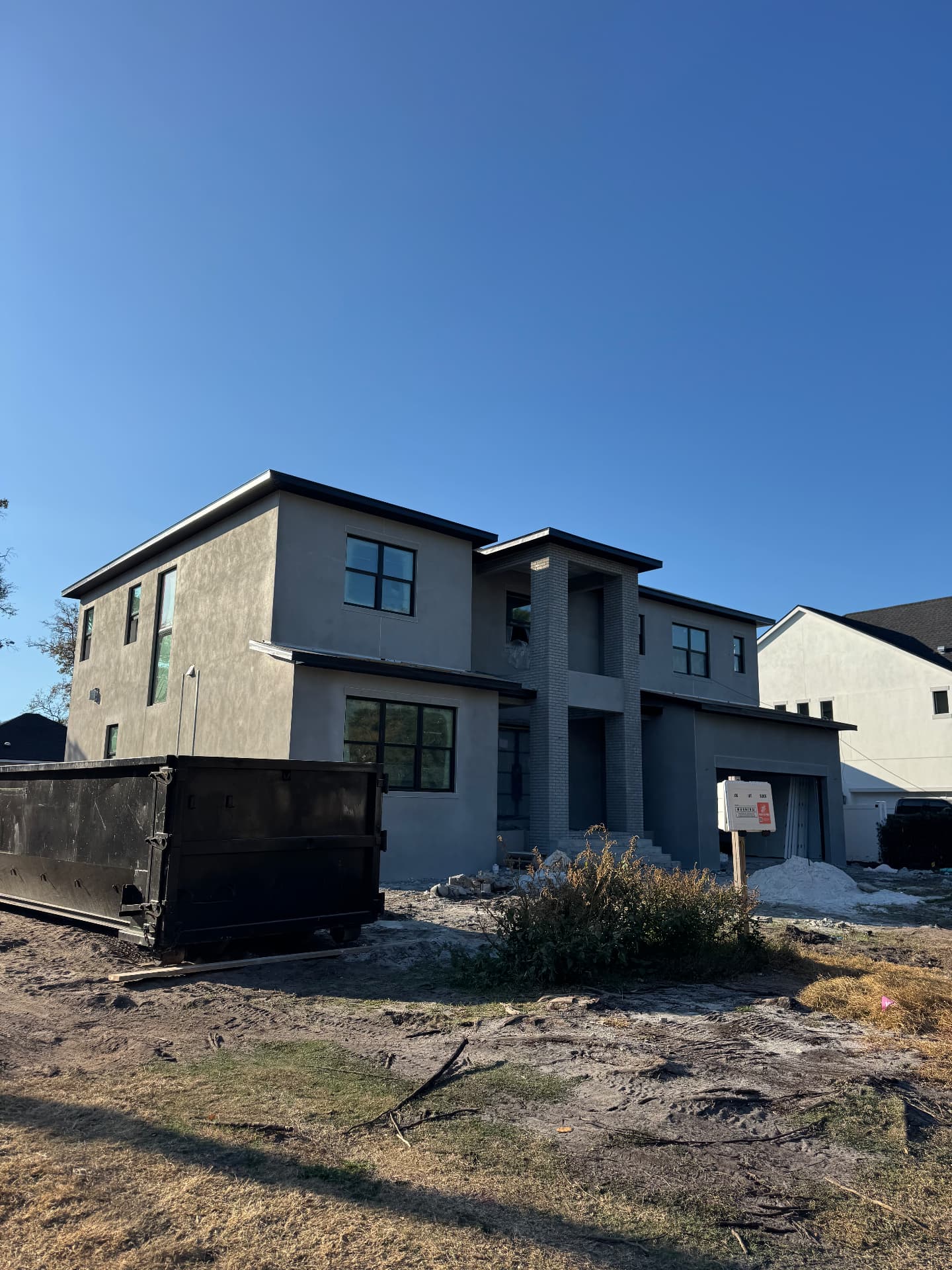 Modern two-story home with dark gray stucco and brick accents